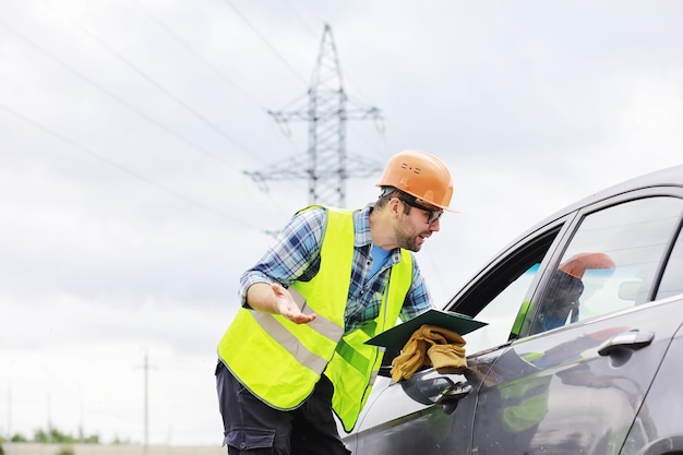 Un homme portant un casque et un uniforme, un électricien sur le terrain. Un ingénieur électricien professionnel inspecte les lignes électriques pendant le travail.