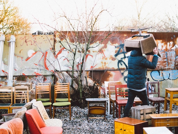 Photo homme portant une chaise sur la tête à l'atelier