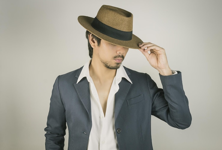 Photo un homme portant un chapeau alors qu'il se tient contre un fond gris