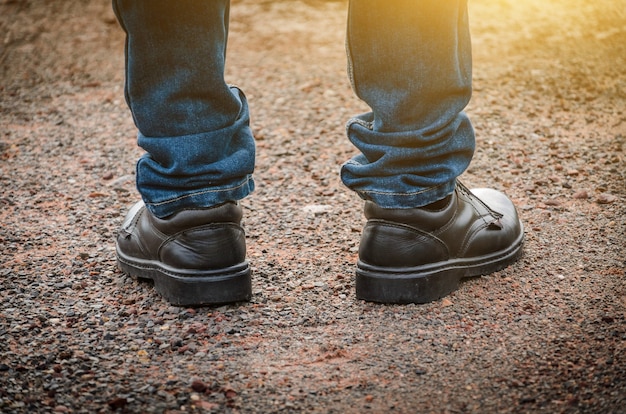 Homme portant des chaussures de sécurité de couleur noire debout sur le sol