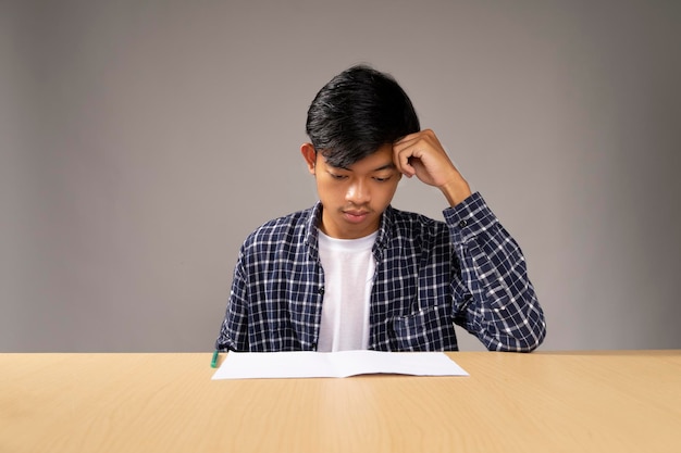 Homme portant une chemise bleue assis stressé en regardant ses documents de travail