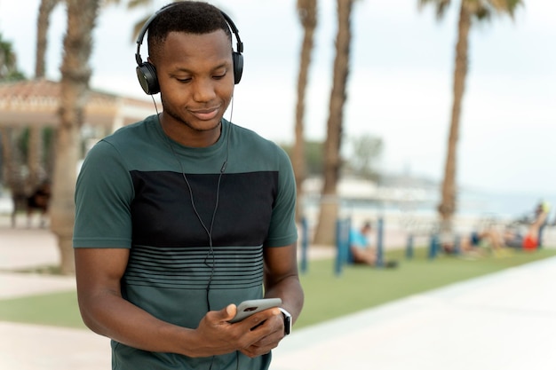 Homme portant des écouteurs debout dans la rue et allumant de la musique sur son smartphone