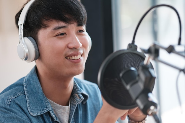 Un homme portant des écouteurs sourit tout en tenant un microphone