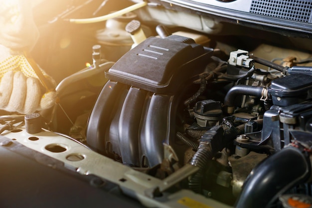 Un homme portant des gants vérifie l'huile dans le moteur d'une voiture