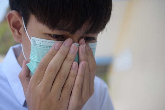 Un homme portant un masque chirurgical pour se couvrir le nez Avec la toux et les éternuements dus à la maladie Afin de prévenir la propagation de virus et de germes à d'autres, le masque facial protège le virus corona 2019