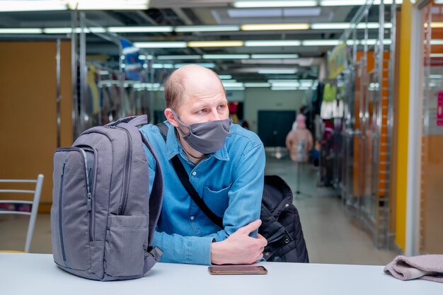 Un homme portant un masque médical attend que son mari se rende au magasin pendant Covid Postform mesure une nouvelle réalité