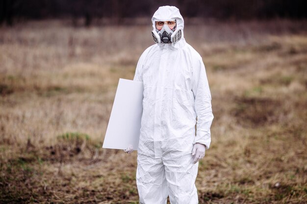 Homme portant un masque médical et une combinaison de protection avec une affiche dans les mains Concept épidémique et médical