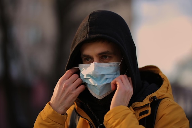 Un homme portant un masque médical dans la rue Le gars portant un masque médical dans la cour