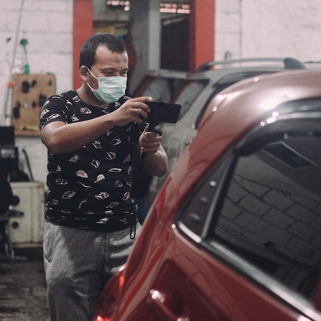 Photo un homme portant un masque photographie une voiture.