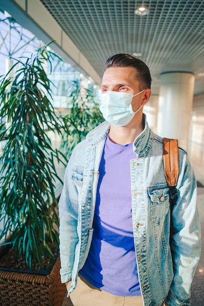 Homme portant un masque pour prévenir le virus dans le salon de l'aéroport international en attente d'un avion de vol.