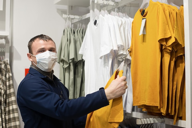 Un homme portant un masque protecteur choisit des vêtements décontractés Commerce de détail Consumérisme