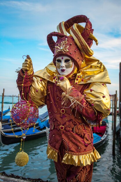 Photo un homme portant un masque vénitien alors qu'il se tient au bord de la mer contre le ciel