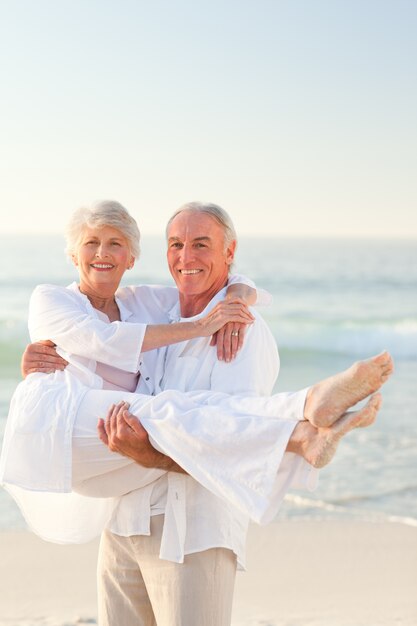 Homme portant sa femme sur la plage