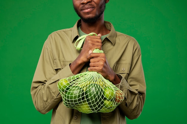 Photo homme portant un sac en filet avec des fruits verts