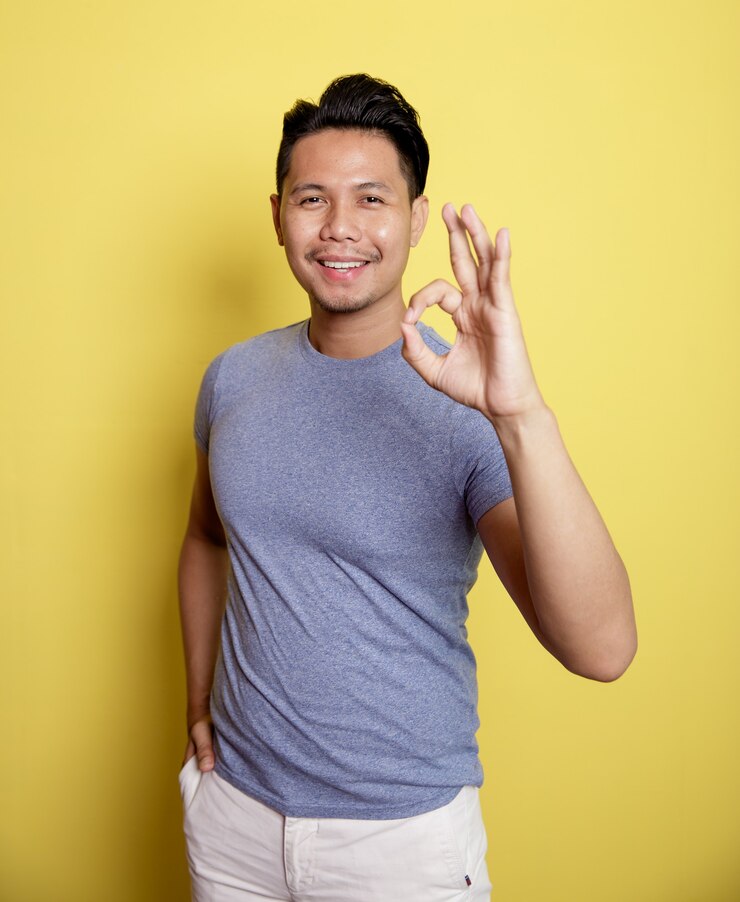 Photo homme portant un t-shirt décontracté expression de sourire montrant signe ok avec il main isolé sur un fond de couleur jaune