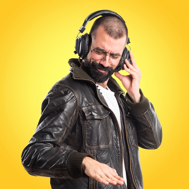 Homme portant une veste en cuir, écoutant de la musique sur un fond coloré