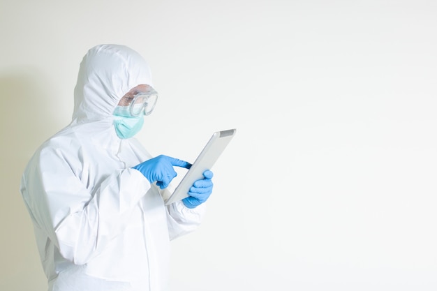 L'homme porte un costume hazmat à l'aide d'une tablette lire une épidémie d'information maladie contagieuse covid19 copy space