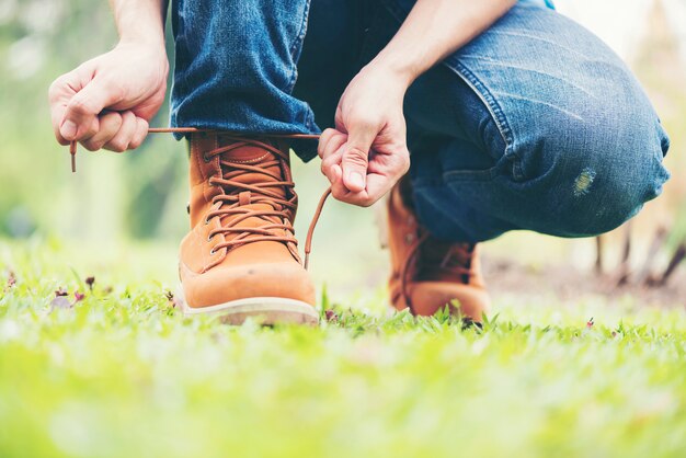 l'homme porte des jeans à genoux pour refaire ses lacets.