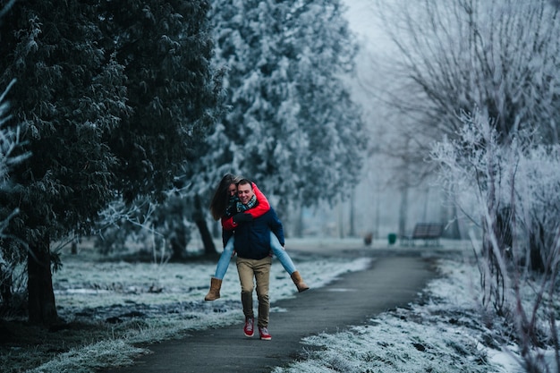 L'homme porte sa petite amie sur le dos dans le parc