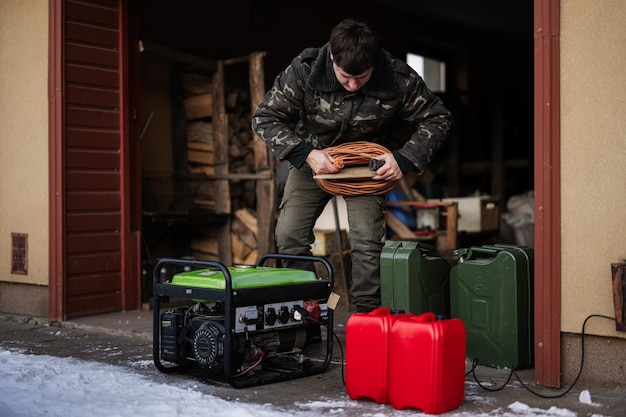 L'homme porte une veste militaire avec un générateur de secours mobile portable à essence