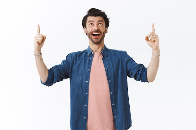 homme, porter un t-shirt rose, une chemise, regarder et pointer du doigt amusé, bouche ouverte fasciné, célébrant joyeusement les vacances