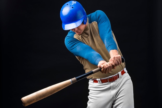 Un homme posant avec un casque et une batte de baseball