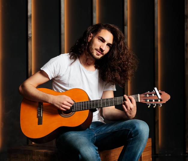 Homme posant avec une guitare acoustique regardant la caméra en studio