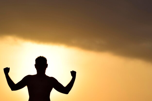 Homme posant avec une posture de force avec espace de copie au coucher du soleil