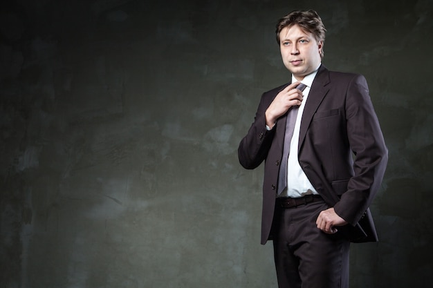 L'homme pose dans son costume devant le mur gris grunge