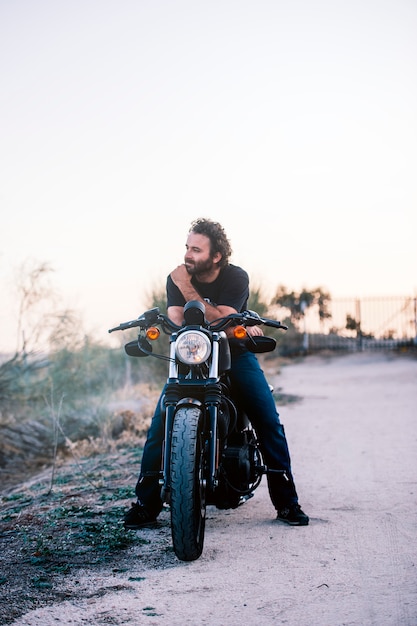 L'homme pose sur sa moto à sunsett