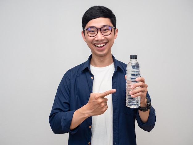 Homme positif porter des lunettes sourire doux pointer du doigt une bouteille d'eau isolée