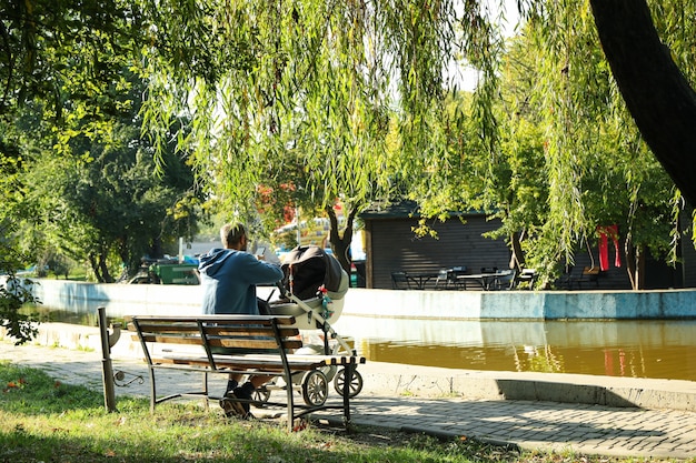 Homme avec poussette assis sur un banc dans le parc de la ville