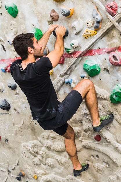 Homme pratiquant l&#39;escalade sur mur artificiel à l&#39;intérieur. Mode de vie actif et concept de bloc.