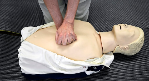 Photo homme pratiquant des techniques de rcr sur mannequin.