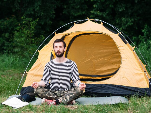 Homme pratiquant le yoga en camping