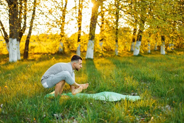 Homme pratiquant le yoga dans un parc au beau coucher du soleil. Mode de vie sain