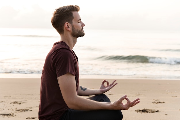 Homme pratiquant le yoga sur la plage