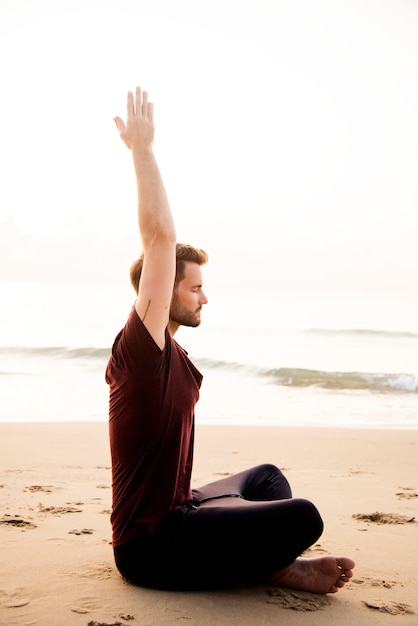 Homme pratiquant le yoga sur la plage