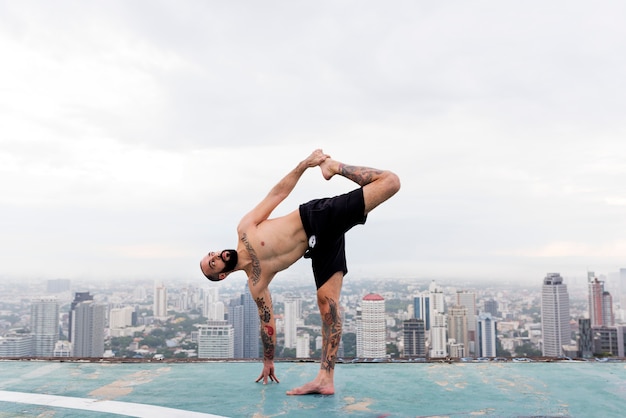 Homme pratiquant le yoga sur le toit
