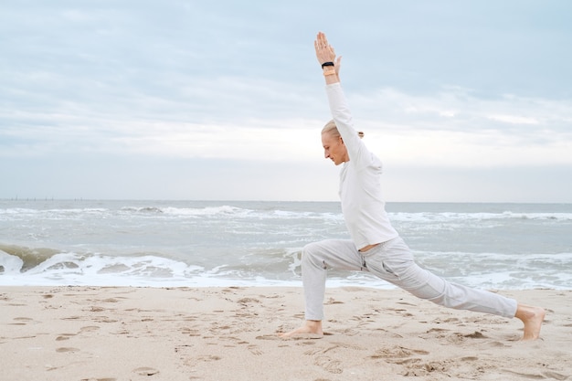 L'homme pratique le yoga sur la plage de la mer adulte pratique le yoga sur la plage