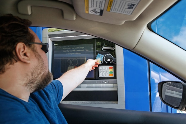 Photo homme prenant de l'argent en espèces à partir d'un guichet automatique à travers un conducteur de banque utilisant le service bancaire de la voiture