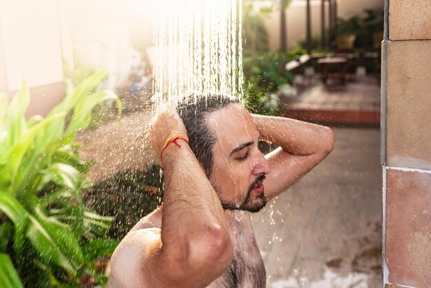 Photo homme prenant une douche extérieure dans un lieu de villégiature de rêve