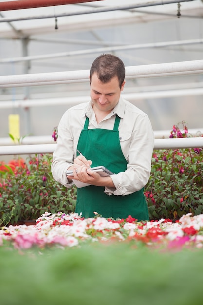 Homme prenant des notes en serre