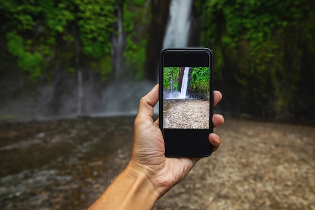 Homme prenant la photo d'une belle cascade