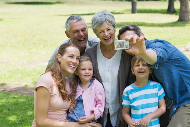 Homme prenant une photo de la famille élargie au parc