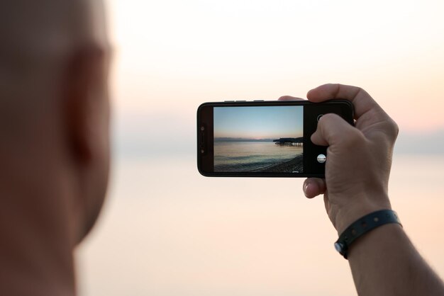 Homme prenant une photo incroyable coucher de soleil à l'aide d'une main de touriste de l'appareil photo du smartphone tenant