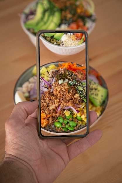 Homme prenant des photos de nourriture hawaïenne à la table poke bowl