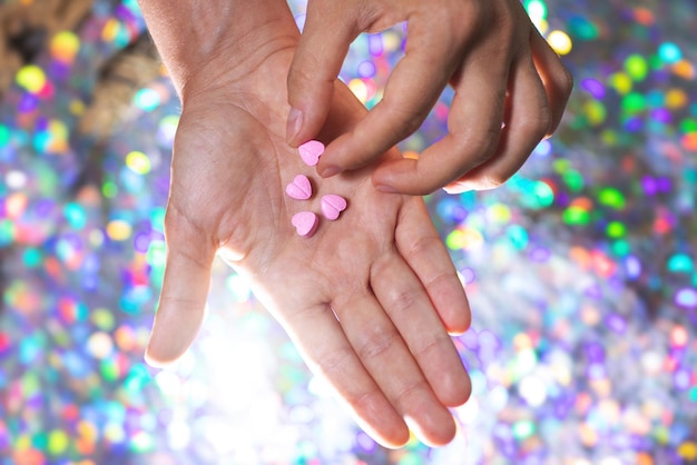 Homme prenant une des pilules en forme de coeur de la paume