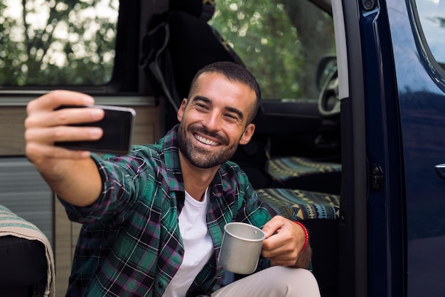 Homme prenant un selfie assis dans la porte de sa camionnette