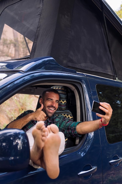 Homme prenant un selfie assis sur son camping-car